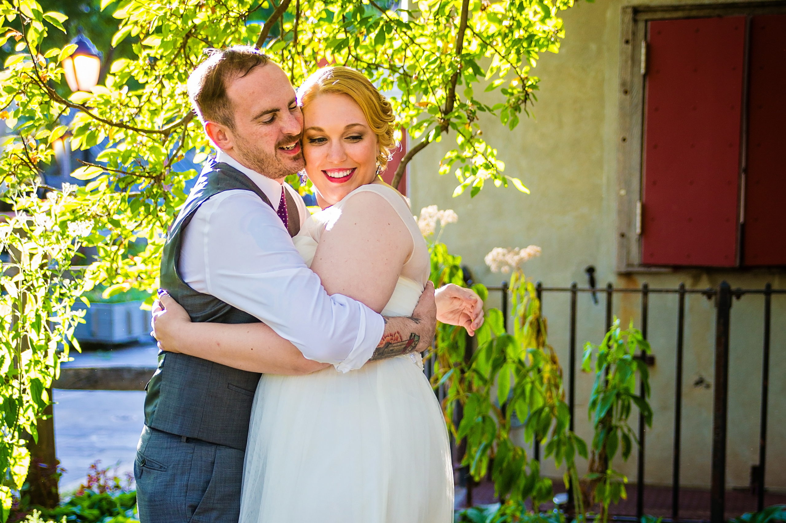 Offbeat bride and groom embrace during their garden wedding.