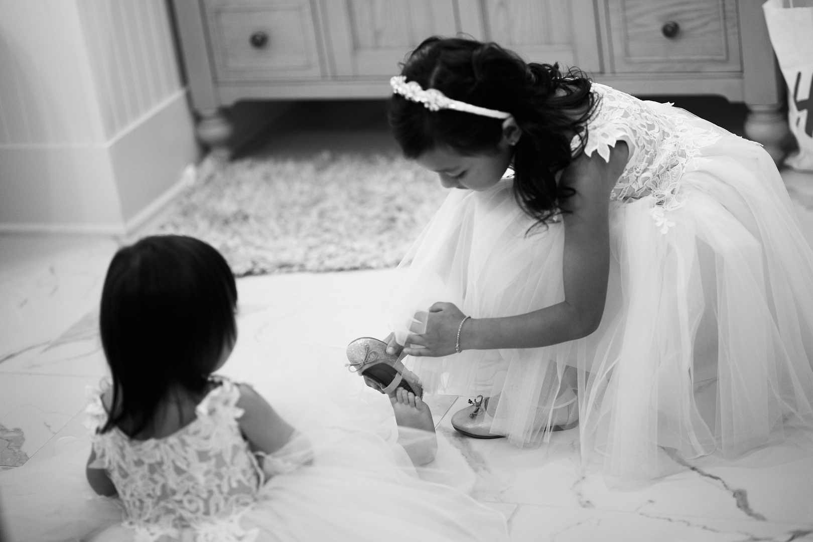 Big sister helping little sister put on flower girl shoes