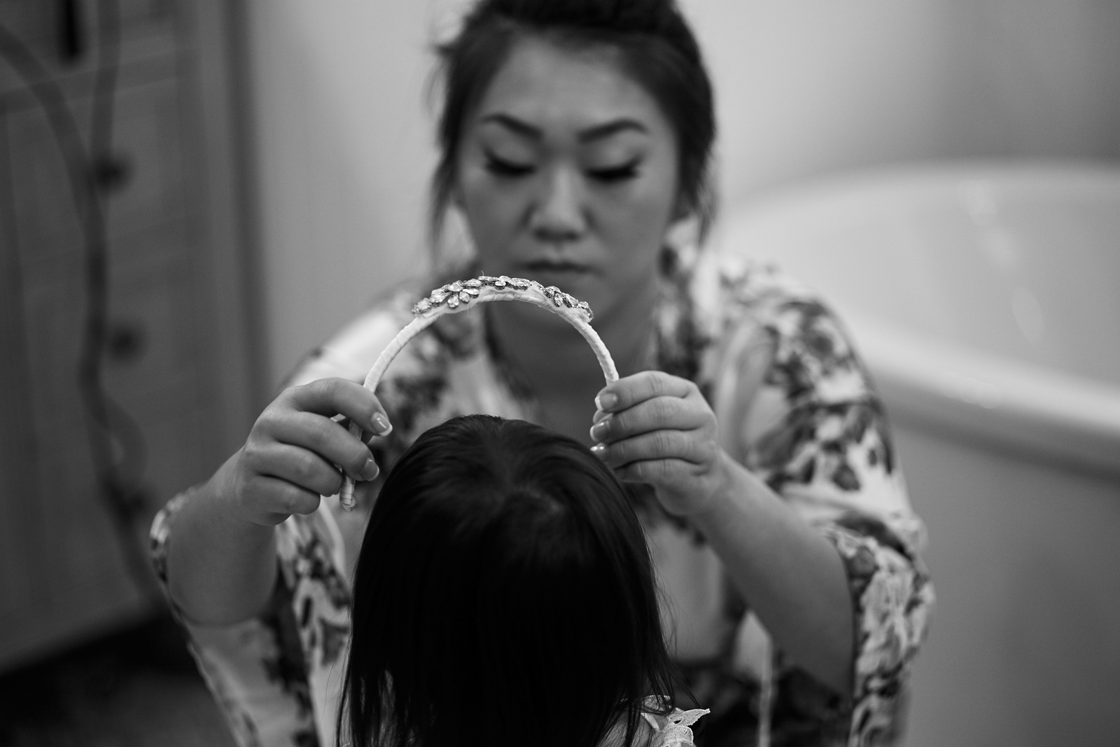 Bride putting tiara on flower girl daughter