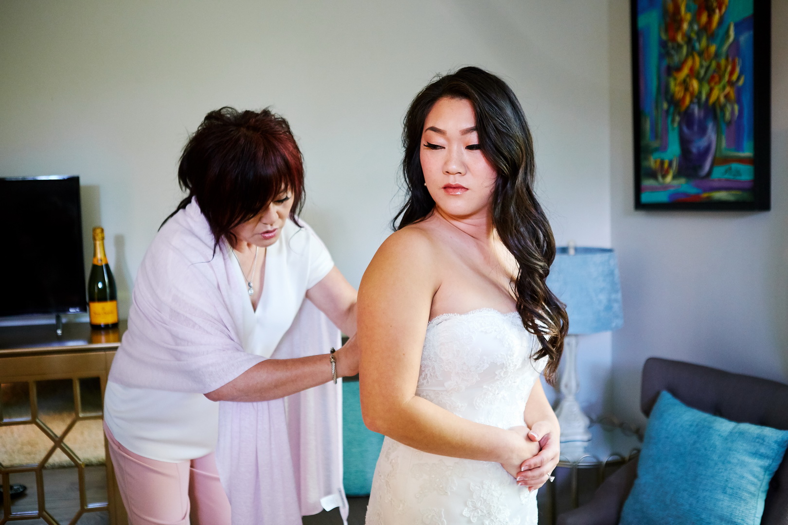 Mother of bride helps bride into wedding dress