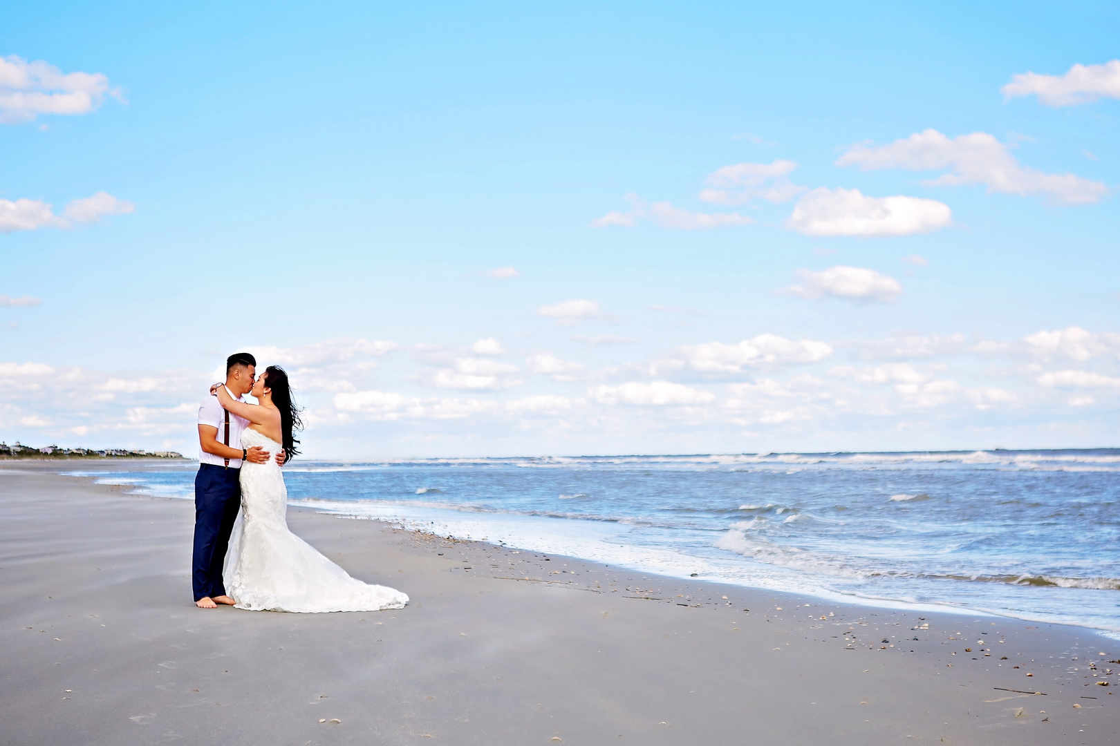 Bride and groom embrace and kiss on the beach in Isle of Palms, SC.