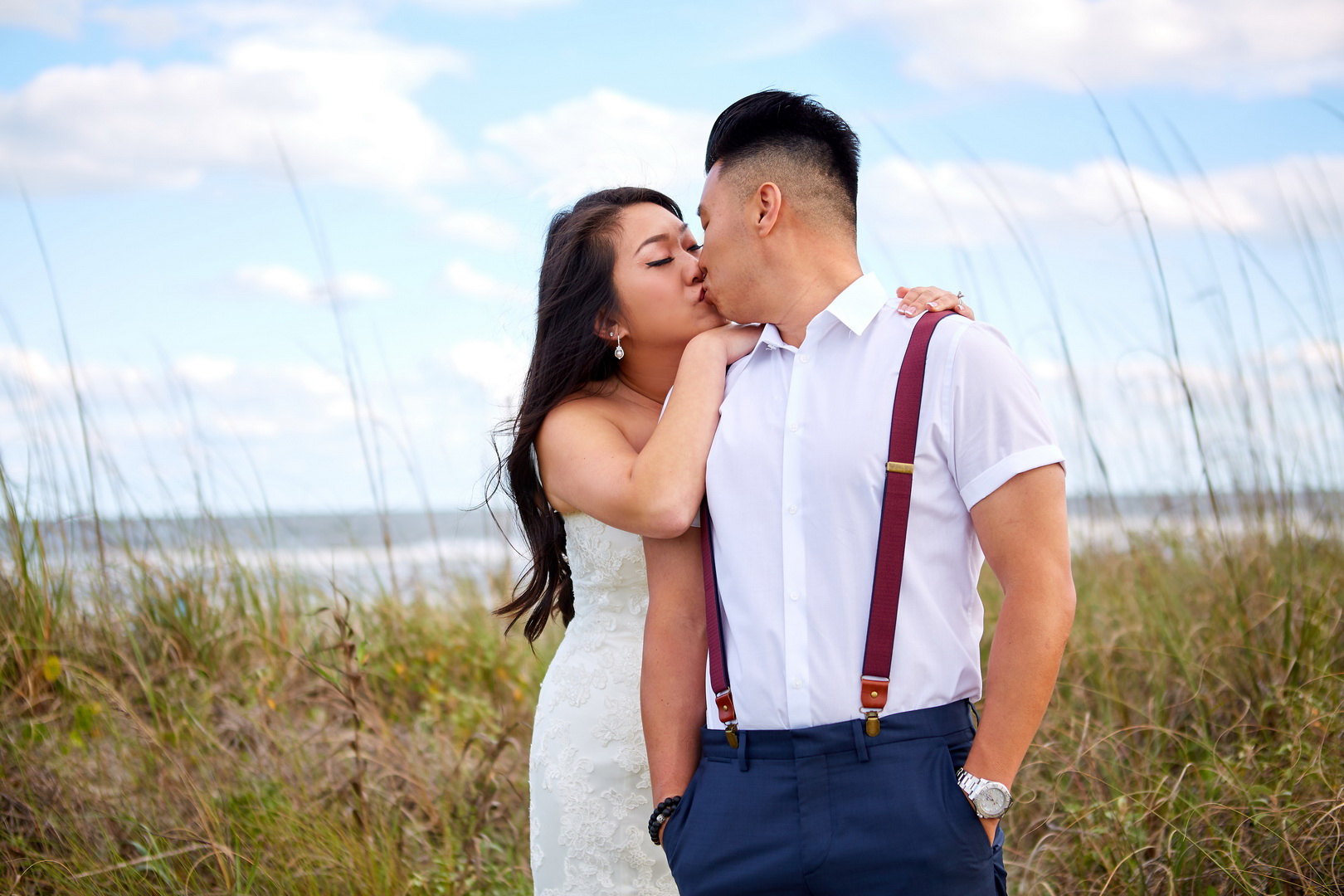 Bride kissing groom over his shoulder on beach grass in Isle of Palms, SC.