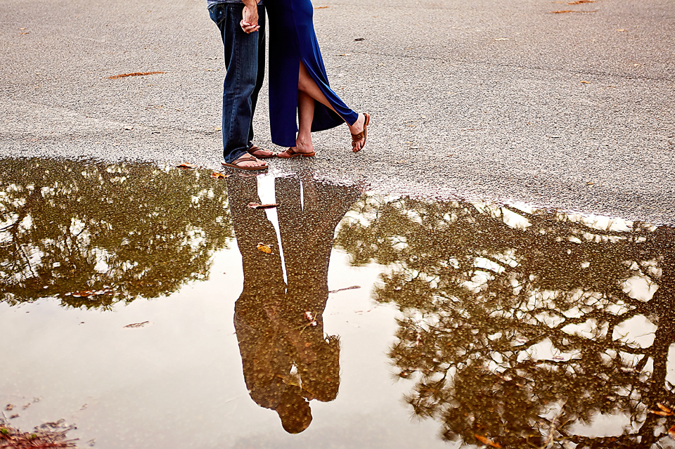  Reflection of a couple in a puddle during a rainy engagement session in Park Circle, North Charleston, SC 
