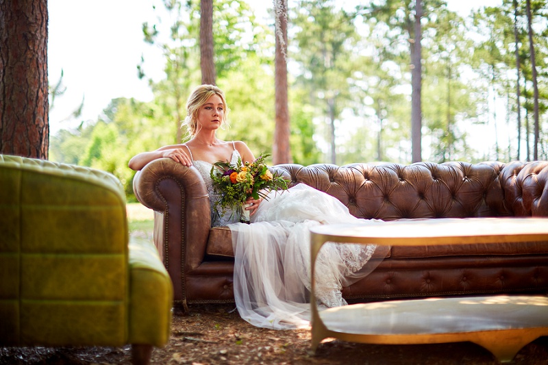 Bride lounging on brown couch, looking into the distance at Charleston Woodlands