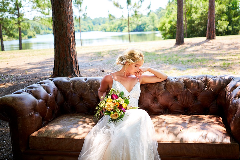 Bride lounging on brown couch with colorful bouquet at Charleston Woodlands