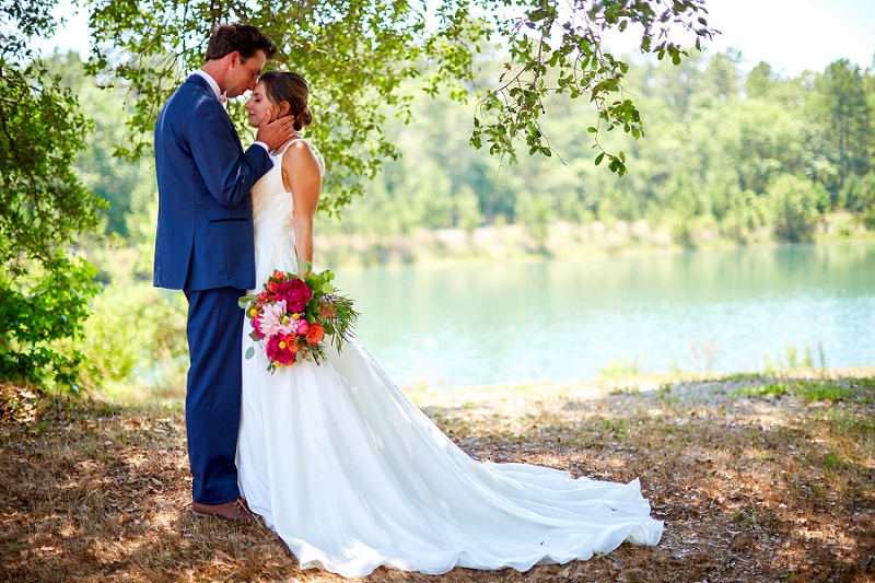 Bride and groom pose together lakeside at Charleston Woodlands