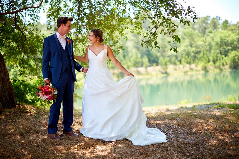 Bride and groom look at each other, lakeside at Charleston Woodlands