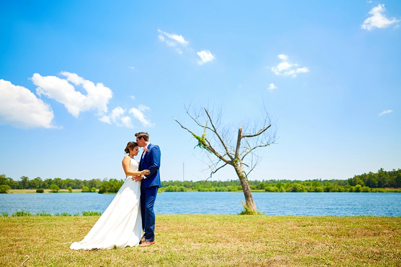 Bride and groom portrait by a tree on the lake at Charleston Woodlands