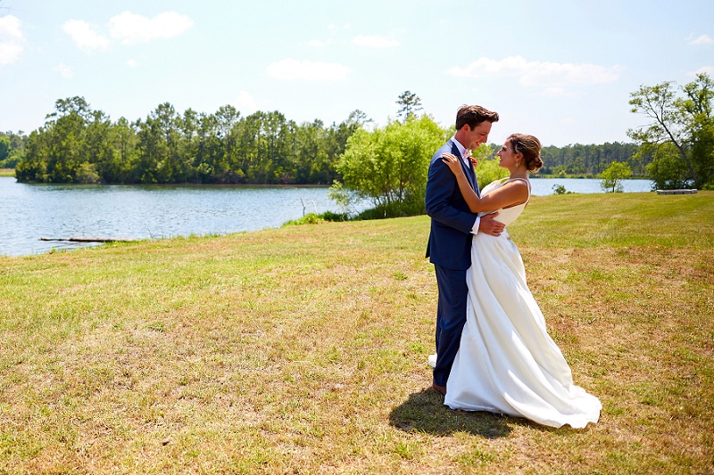 Bride and groom look at each other at the lake in Charleston Woodlands