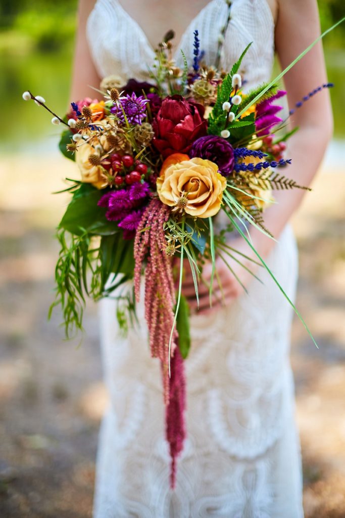 Close up of bride's lace wedding dress and colorful bridal bouquet