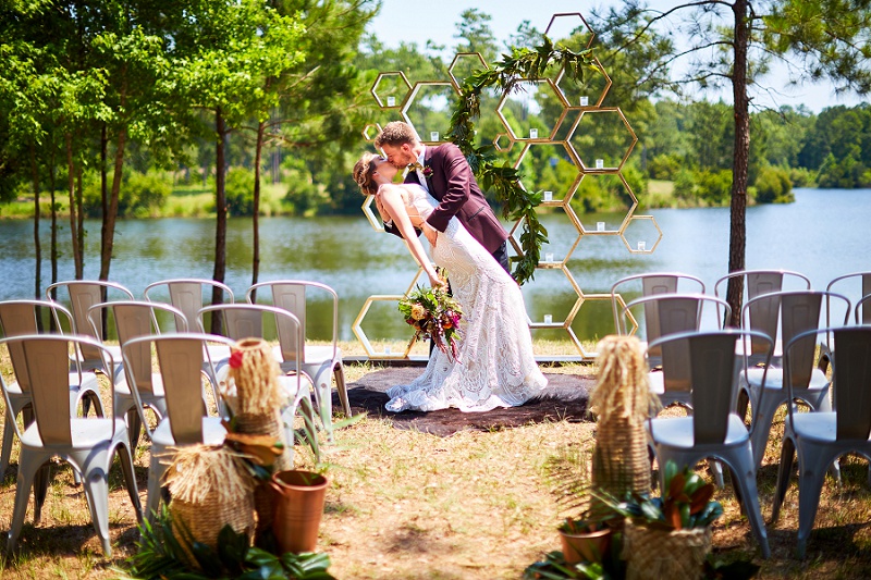 Groom dipping bride at the arbor during outdoor wedding ceremony
