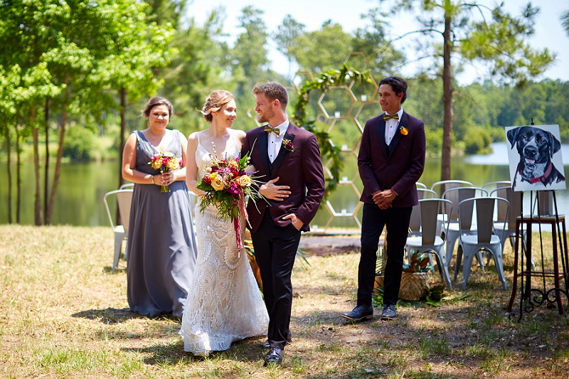 Bride and groom walking up the aisle for outdoor wedding ceremony recessional, with bridesmaid and groomsman looking on.