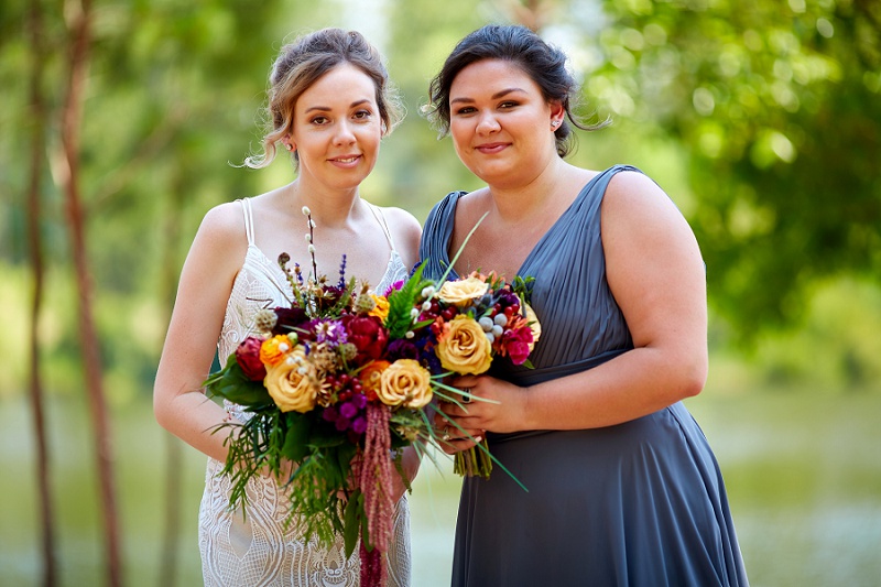 Portrait of bride and bridesmaid holding colorful bouquets