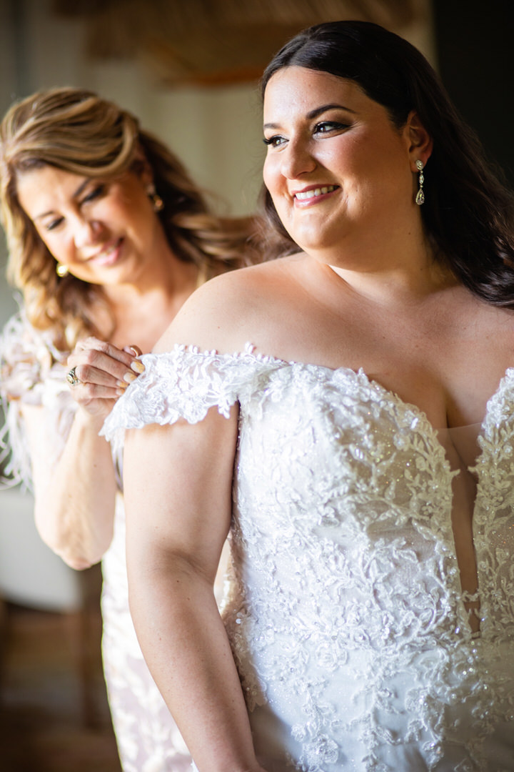 Mother helps bride into her wedding dress by the window  - photographed by Charleston wedding photographer Luxe By Lindsay Photography