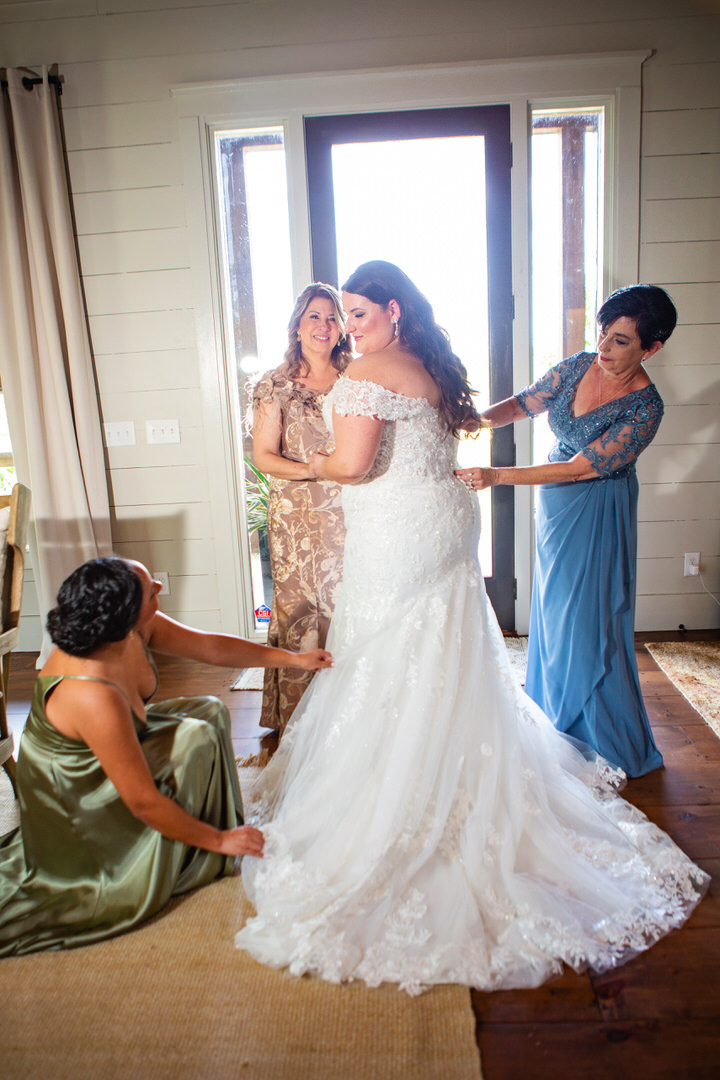 Bridesmaids help bride get into her wedding dress and with finishing touches at Eden at Gracefield wedding  - photographed by Charleston wedding photographer Luxe By Lindsay Photography
