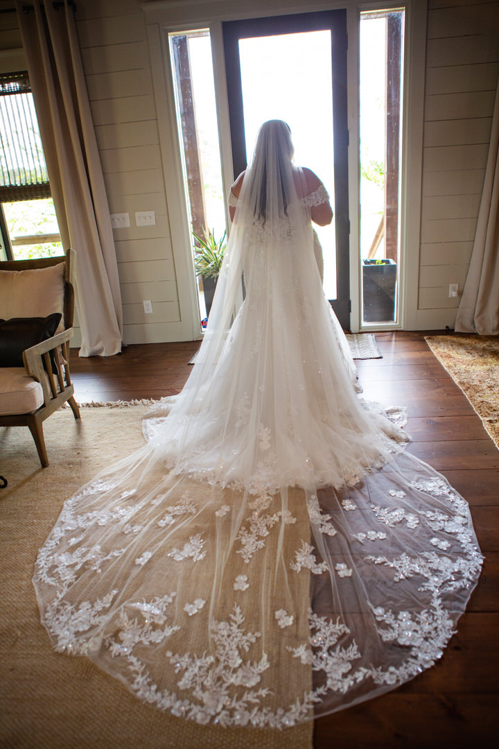 Silhouette of back of bride showing her wedding dress and cathedral veil detail at Eden at Gracefield, SC wedding venue  - photographed by Charleston wedding photographer Luxe By Lindsay Photography