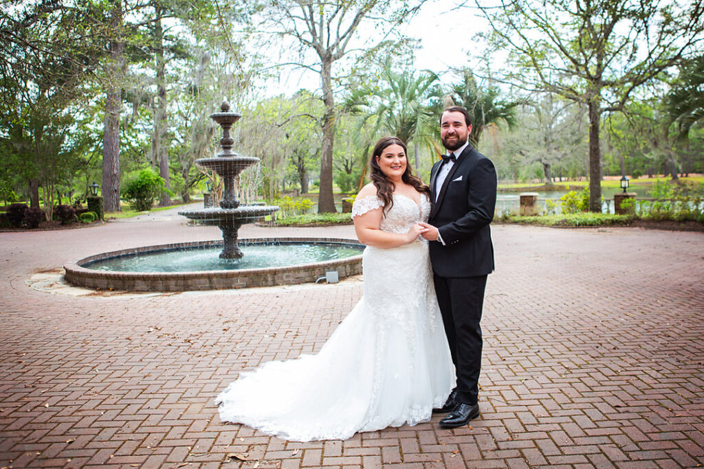 Bride and groom pose and smile in front of a fountain at Eden at Gracefield, in Walterboro, SC - photographed by Charleston wedding photographer Luxe By Lindsay Photography