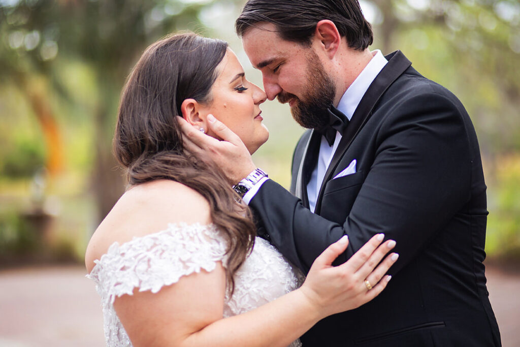 Close up portrait of bride and groom facing each other, with closed eyes and touching noses. Groom's hand is on bride's face, and her hand is on his arm  - photographed by Charleston wedding photographer Luxe By Lindsay Photography