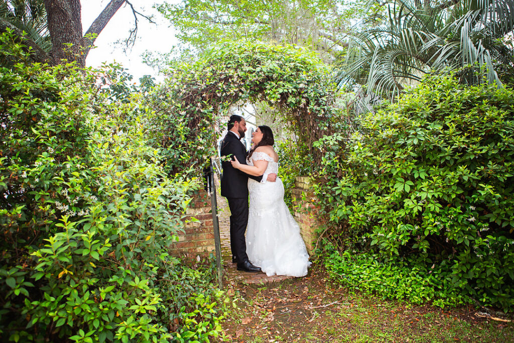 Bride and groom wedding portrait underneath an arch of leaves in a garden setting at Eden at Gracefield in Walterboro, Charleston wedding venue - photographed by Charleston wedding photographer Luxe By Lindsay Photography