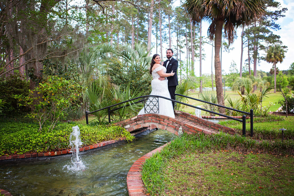 Portrait of bride and groom standing on a bridge over a small water feature in a garden at Eden at Gracefield  - photographed by Charleston wedding photographer Luxe By Lindsay Photography
