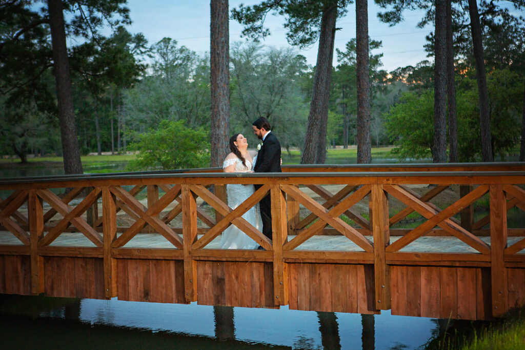 Bride and groom look at each other while on a bridge over a lake at Eden at Gracefield during dusk - photographed by Charleston wedding photographer Luxe By Lindsay Photography