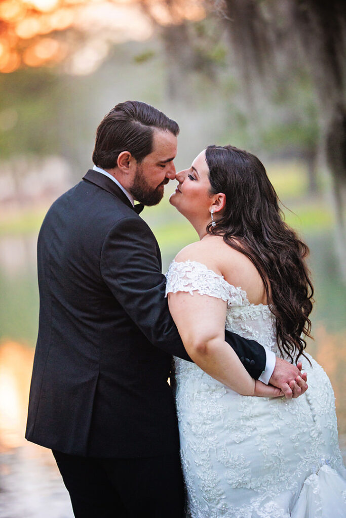 Bride and groom touch noses while holding hands with their hands behind the bride's back at Eden at Gracefield - photographed by Charleston wedding photographer Luxe By Lindsay Photography